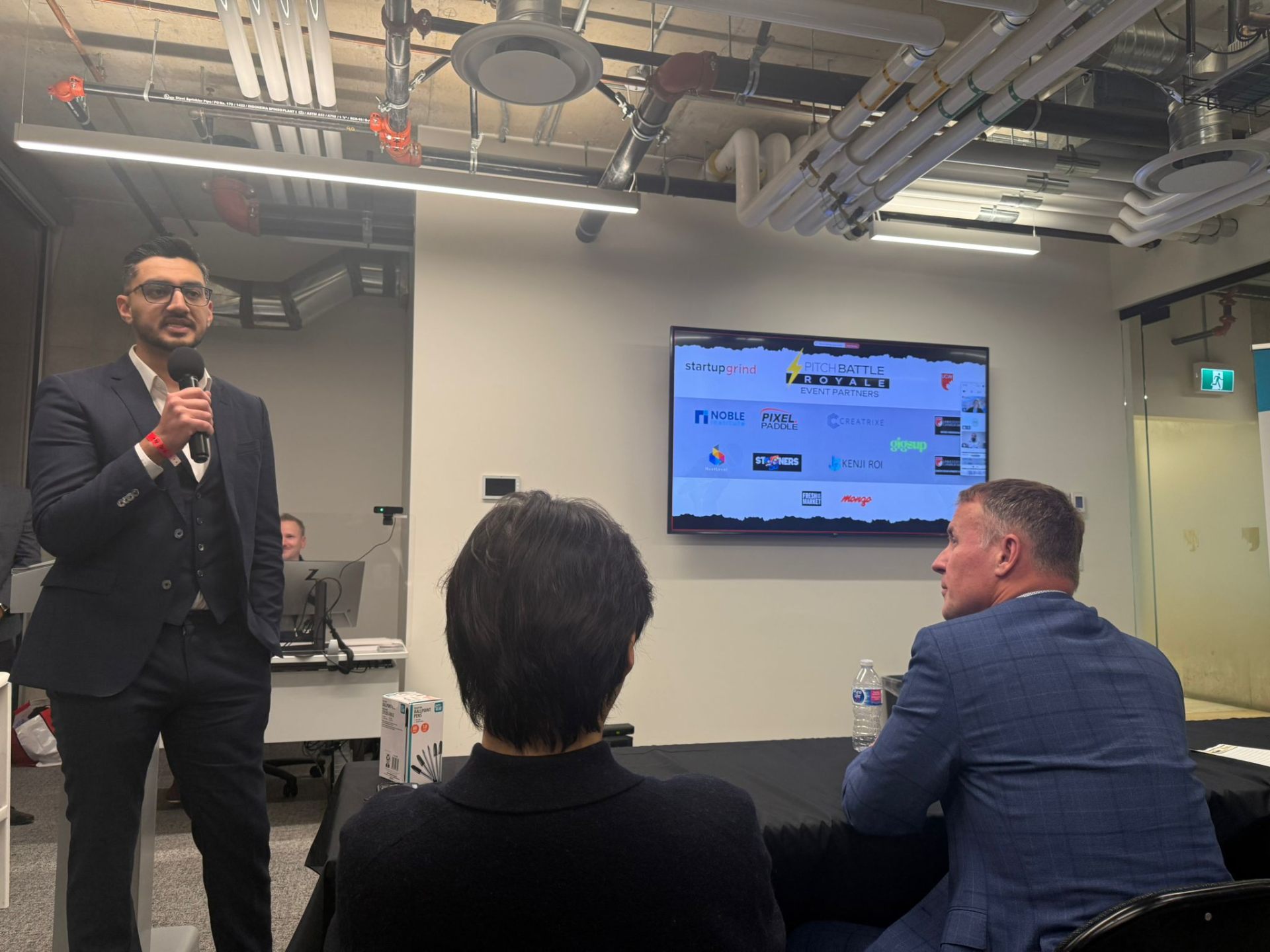 Speaker addressing audience with event partners on screen