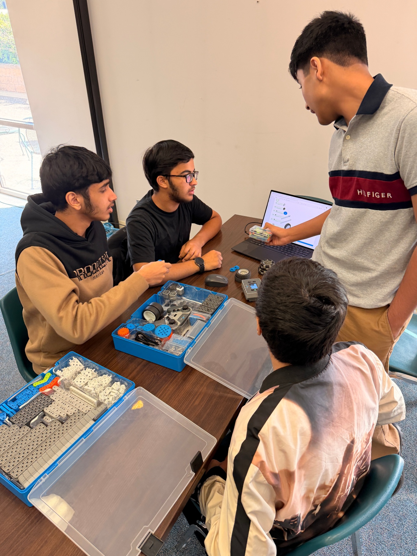 Mentor guiding students through coding and engineering on laptops